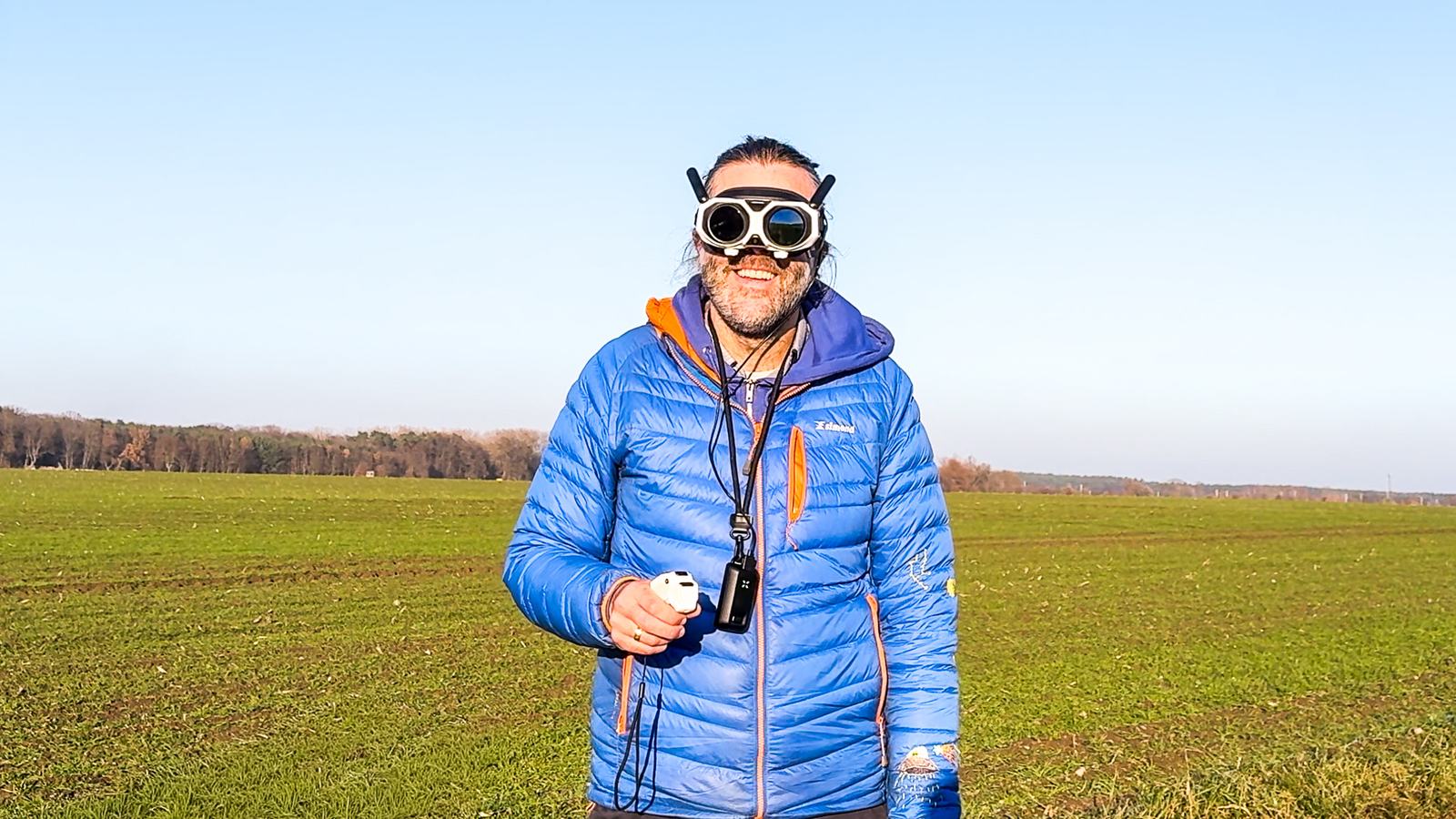 Marc grinst im Feld mit der FPV-Brille der Antigravity A1 auf der Stirn und dem Grip-Controller in der Hand