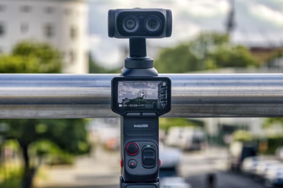 Insta360 Luna Ultra steht frei auf einer bemoosten Mauer vor unscharfer Stadtkulisse