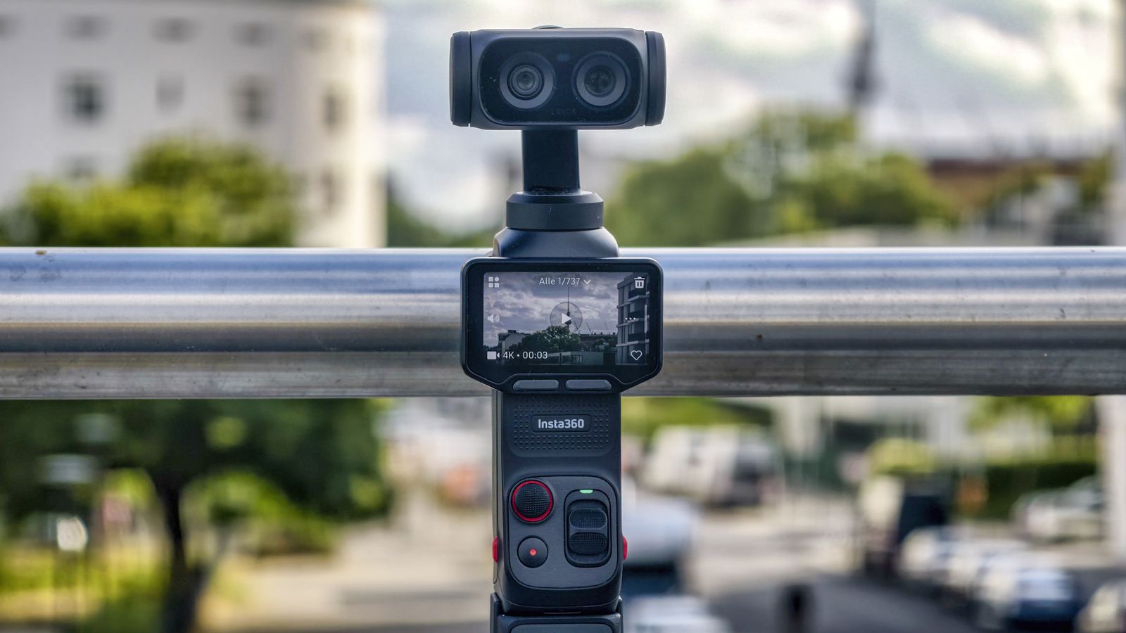 Insta360 Luna Ultra steht frei auf einer bemoosten Mauer vor unscharfer Stadtkulisse