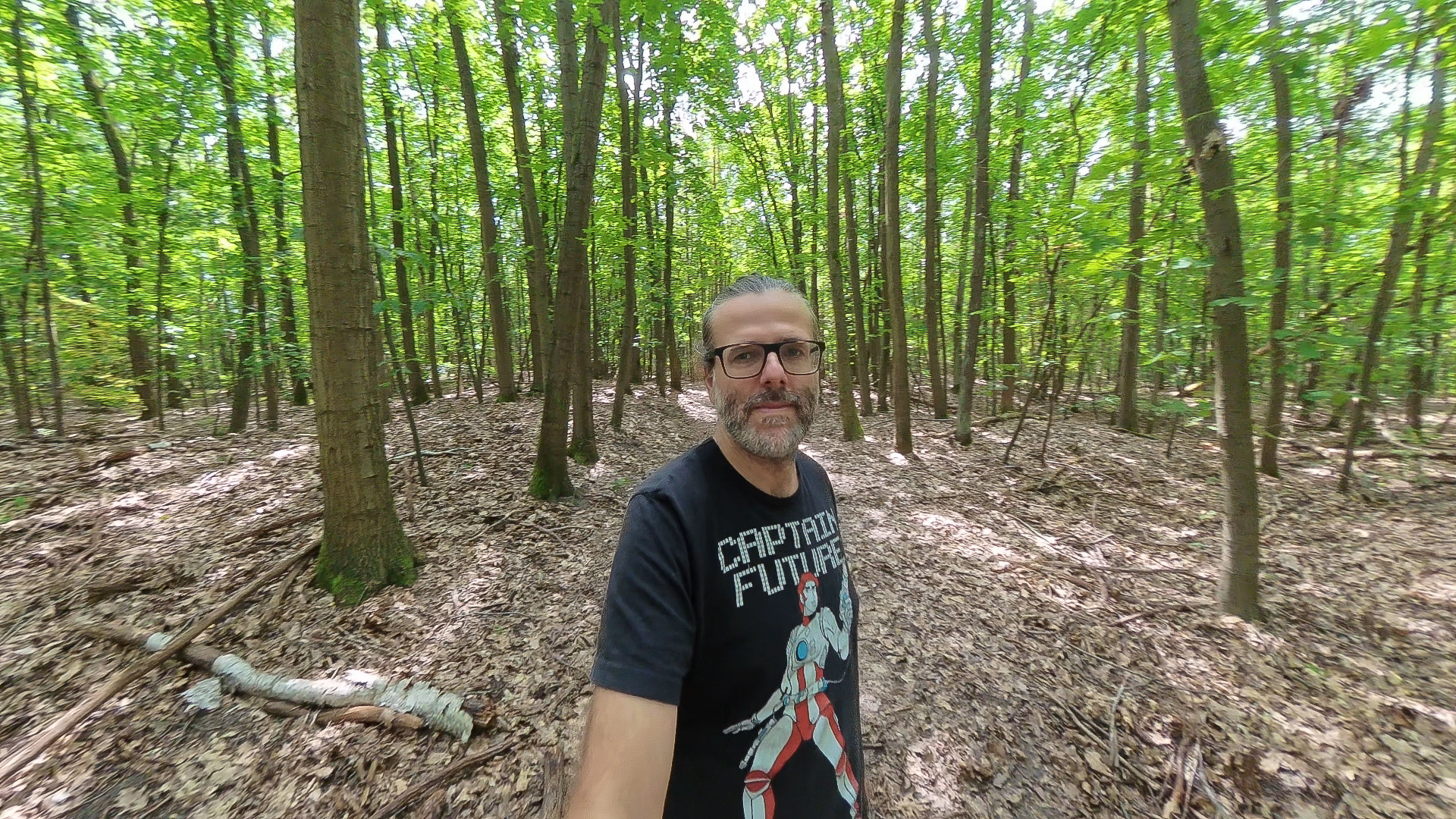 Ausschnitt aus einem 8K-360°-Video der Insta360 X4 Air: schattiger Waldweg mittags, Marc im Bild, Baumstämme und Blätter mit sichtbar weniger Details