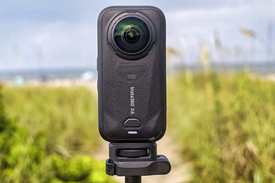 Die Insta360 X6 steht aufrecht im Sand, dahinter Meer und Himmel