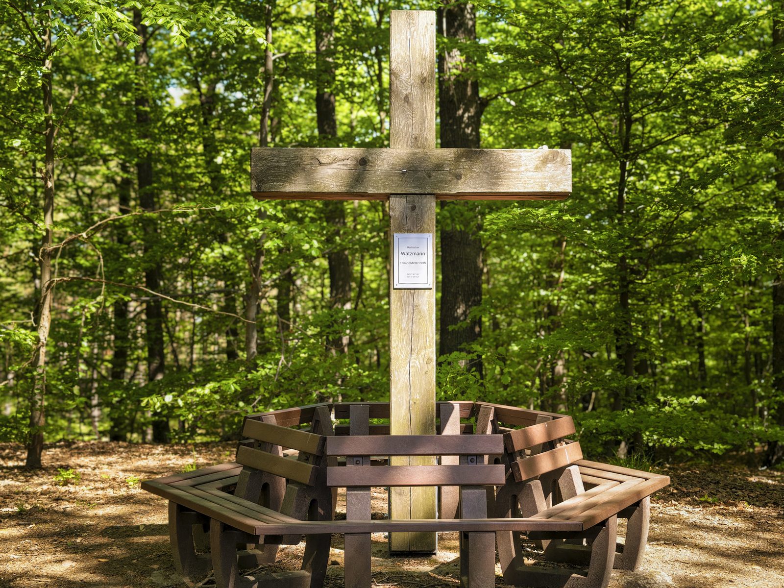 Gipfelkreuz aus Holz mit Rundbank auf dem Märkischen Watzmann, am Kreuz das Schild mit der Höhenangabe 1.062 dMeter